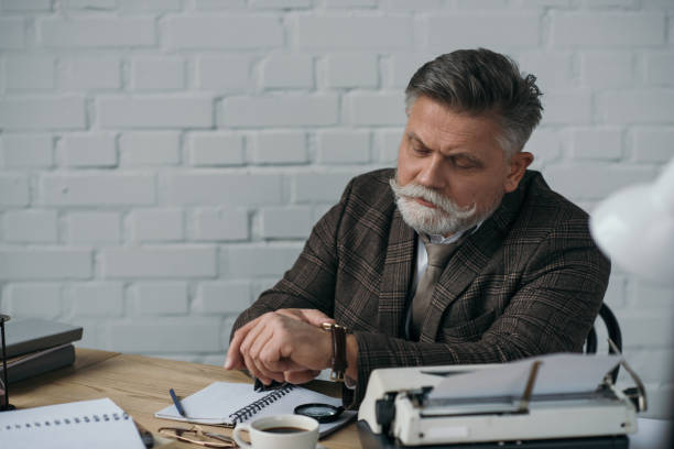 istock serious senior writer putting on his vintage watch 923405402