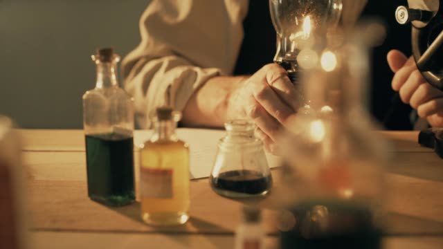 turn of the century scientist moves a lamp closer to the microscope