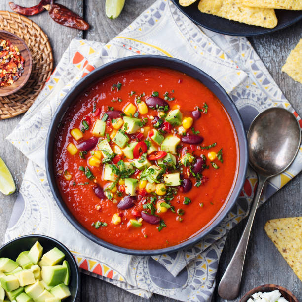istock Mexican tomato, bean, bell pepper soup in black bowl. Top view 923414494