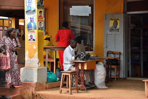 Kampala, Uganda - Aug 28, 2010: Shop of a tailor on a suburban street in Kampala. Unidentified man with sewing machine. Small business wide spread between locals