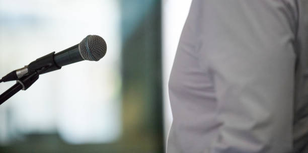 Public speeker in front of microphone Midsection of unrecognizable man giving speech, standing in front of microphone announce stock pictures, royalty-free photos & images