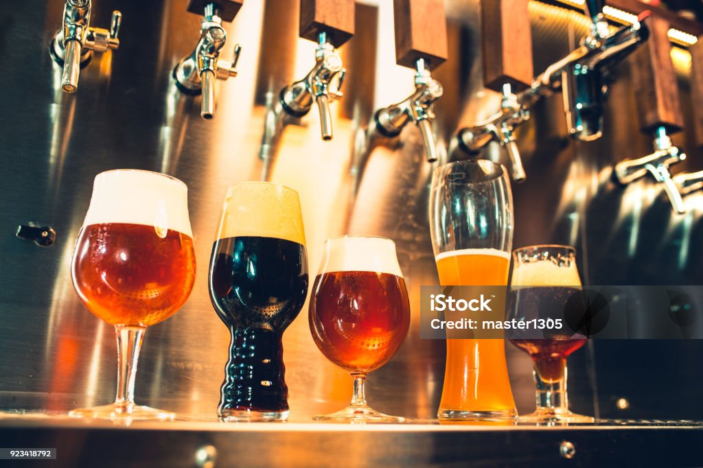 Beer taps in a pub The beer taps in a pub. nobody. Selective focus. Alcohol concept. Vintage style. Beer craft. Bar table. Steel taps. Shiny taps. Glass of beer Beer - Alcohol Stock Photo