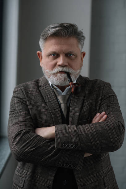 istock senior man in tweed costume smoking pipe and looking at camera 923430030