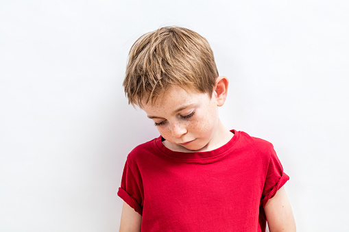 disappointed little child looking down expressing solitude, disillusion, sadness or education and parent problems, white background
