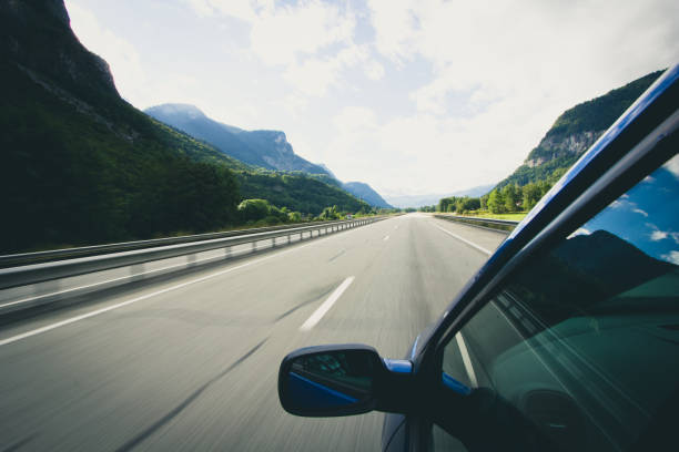 istock A car speeds along an empty motorway with mountains at either side 923434602