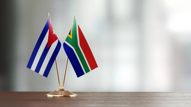 istock Cuban And South African Flag Pair On A Desk Over Defocused Background 923435122