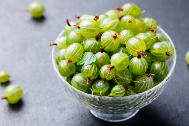 istock Gooseberries in glass bowl on black stone slate background. Copy space. 923438718
