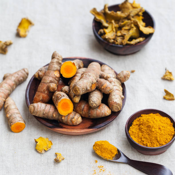 istock Fresh and dried turmeric roots in a wooden bowl. Grey textile background. Copy space. 923451124