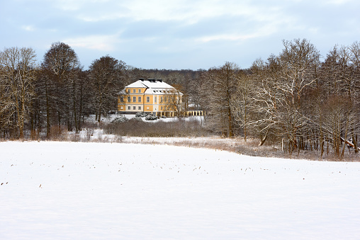 Johannishus, Sweden - February 22, 2018: Documentary of everyday life and environment. The Johannishus castle seen among bare trees in winter woodland landscape.