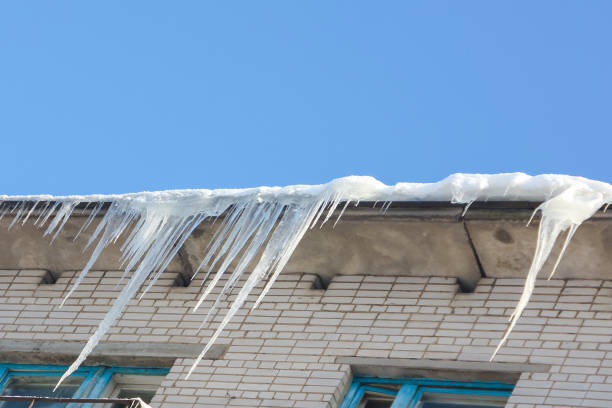 istock Large, sharp icicles hang from the roof. Dangerous icicles on the roof. 923466682