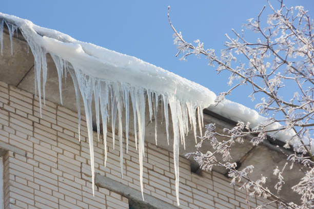 istock Large, sharp icicles hang from the roof. Dangerous icicles on the roof. 923466684
