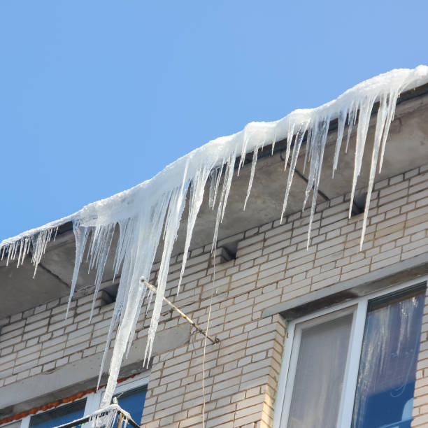 istock Large, sharp icicles hang from the roof. Dangerous icicles on the roof. 923466748