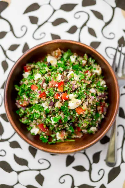 Healthy salad bowl from above. This healthy dish mixes tabbouleh & greek style salads, using fresh parsley herb, olives, onions, feta and replacing the bulgur usually found in tabouleh with quinoa.