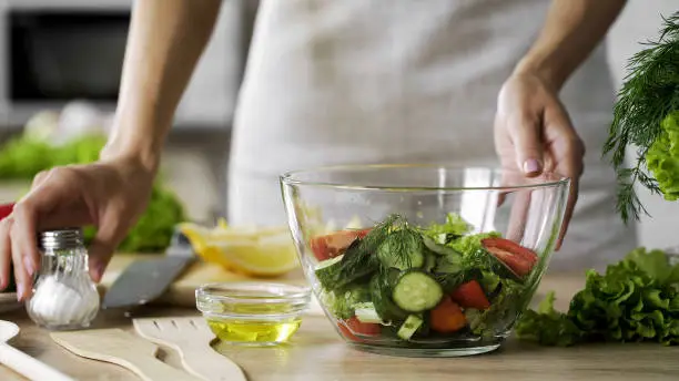 Housewife taking saltshaker on table for seasoning lunch salad, tasty appetizer, stock footage