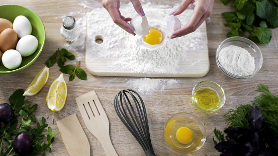 Female cook adding egg in flour, preparing dough for making homemade pancakes, stock footage