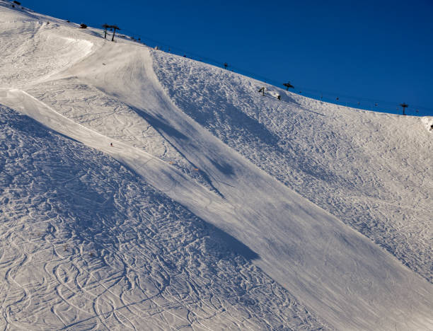 istock Steep gradient piste in Italian Alps with lone expert snowboarder heading down, against a beautiful blue sky 923494464
