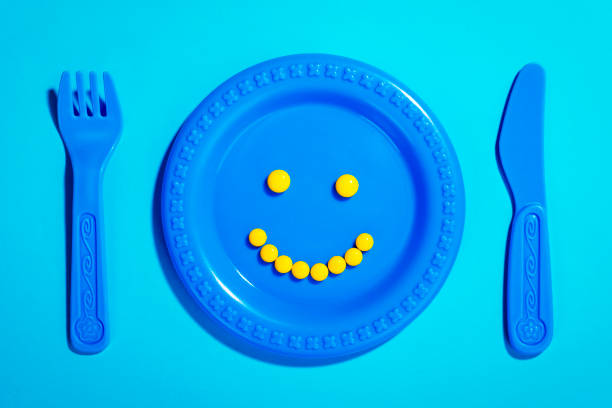 Smiley face made of yellow pills on childrenâs plate and cutlery toy.