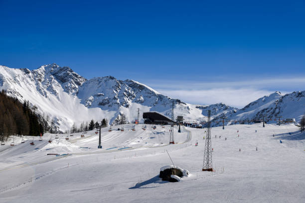 Unidentifiable skiers at ski resort in Pila, Valle d'Aosta, Italy with chairlift and mountain backdrop and copy space Unidentifiable skiers at ski resort in Pila, Valle d'Aosta, Italy with chairlift and mountain backdrop and copy space - winter sports concept pila stock pictures, royalty-free photos & images