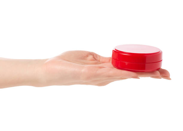 istock Face body cream in a red jar in hand 923497610