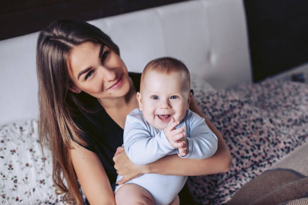 istock Young mother and the small child pose sitting on a bed 923497784