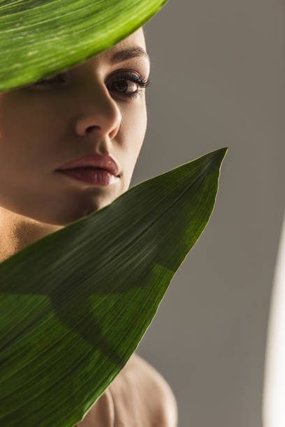 istock attractive girl with green leaves, isolated on grey 923498094