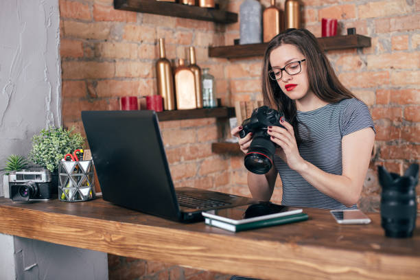 istock Young freelancer girl is working with notebook and photo camera in loft interior 923498312
