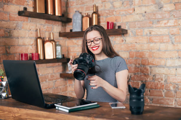 istock Young freelancer girl is working with notebook and photo camera in loft interior 923498326