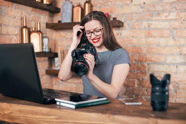 istock Young freelancer girl is working with notebook and photo camera in loft interior 923498346