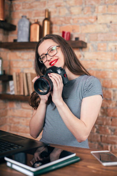 istock Young freelancer girl is working with notebook and photo camera in loft interior 923498354