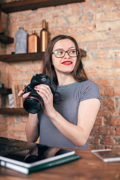istock Young freelancer girl is working with notebook and photo camera in loft interior 923498358