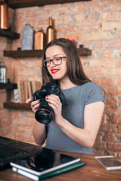 istock Young freelancer girl is working with notebook and photo camera in loft interior 923498384