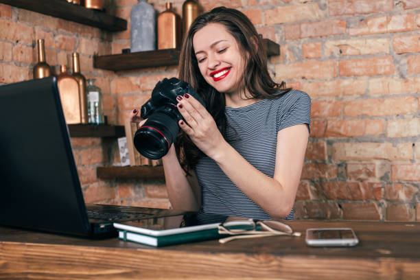 istock Young freelancer girl is working with notebook and photo camera in loft interior 923498400