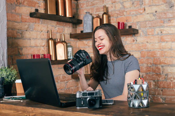 istock Young freelancer girl is working with notebook and photo camera in loft interior 923498430