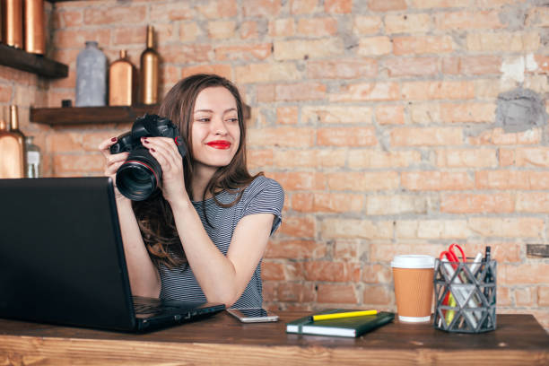 istock Young freelancer girl is working with notebook and photo camera in loft interior 923498452