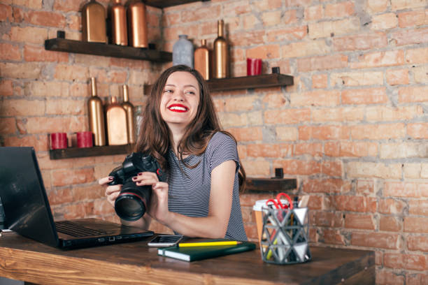 istock Young freelancer girl is working with notebook and photo camera in loft interior 923498482