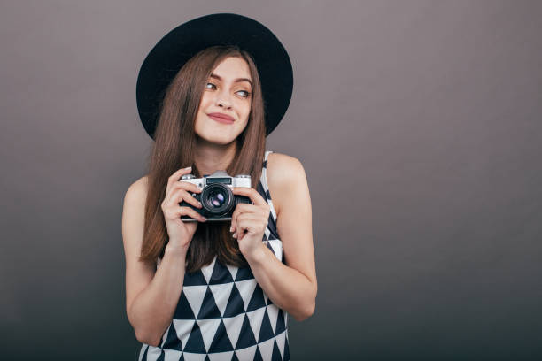 灰色の壁の背景にレトロなカメラでスタイリッシュな女性写真家。コピー スペース イメージ - picture hat ストックフォトと画像