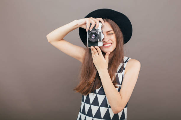 灰色の壁の背景にレトロなカメラでスタイリッシ��ュな女性写真家。コピー スペース イメージ - picture hat ストックフォトと画像