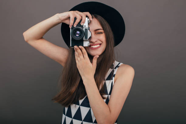 灰色の壁の背景にレトロなカメラでスタイリッシュな女性写真家。コピー スペース イメージ - picture hat ストックフォトと画像