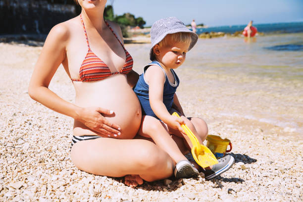 妊娠中の母親と彼女の息子かわいい幼児子供遊んで、夏の時間で海のビーチでリラックスします。 - child beauty mother little boys ストックフォトと画像