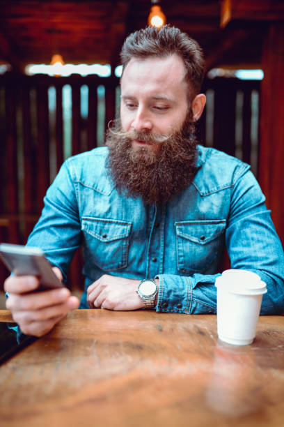 istock Handsome Hipster Person Texting and Drinking Coffee in Cafe 923527012