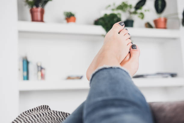 Woman's feet up on the coach against white wall. Beauty, fashion blogging , freelancer concept. Pedicure nail polish design. Copy space