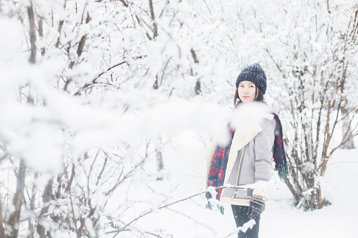 portrait of young woman standing in snowy woods,looking at camera.