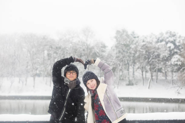 young couple standing on a snow-covered wooden bridge,China.