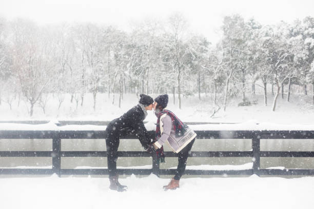 young couple standing on a snow-covered wooden bridge,China.