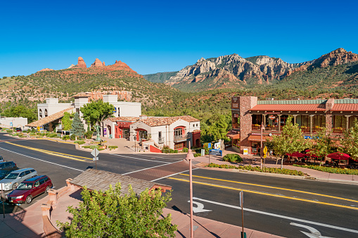 Street with stores, hotel and scenic mountains in uptown Sedona Arizona USA on a sunny day.
