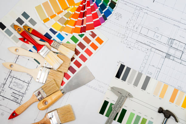 istock Professional decorator using a digital tablet, work tools, painting rollers and color swatches all around, top view 923550062
