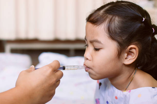 Mother giving medicine to her daughter Mother giving medicine to her daughter. Sick asian little child girl getting liquid medicine with syringe in the hospital. child liquid medicine stock pictures, royalty-free photos & images