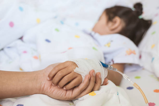 Mother hand holding sick daughter hand who have IV solution bandaged with love and care Mother hand holding sick daughter hand who have IV solution bandaged with love and care while she is sleeping on bed in the hospital girl patient stock pictures, royalty-free photos & images