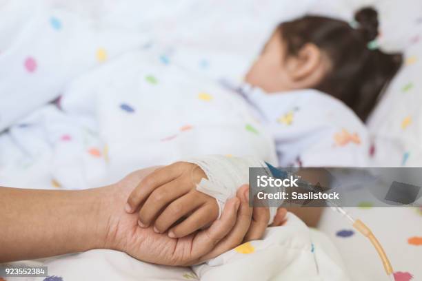 Mother Hand Holding Sick Daughter Hand Who Have Iv Solution Bandaged With Love And Care Stock Photo - Download Image Now