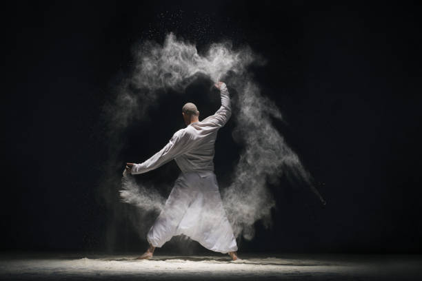 istock Male doing yoga in white dust cloud rearview 923556136